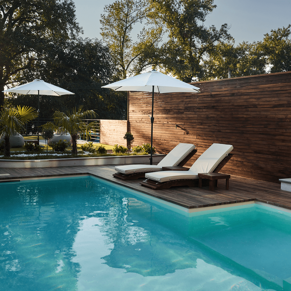 Poolside loungers with umbrellas and trees